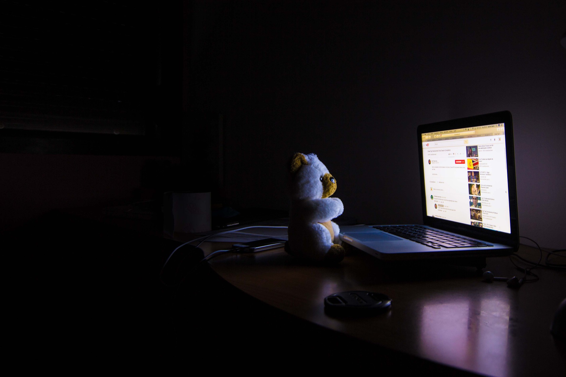 Teddybär schaut nachts Filme am Computer